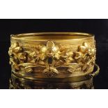 A 19th century gilt metal hinged bangle with floral decoration in high relief, 2.5 cm wide