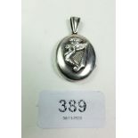 A silver oval locket applied harp and caryatid motif to front, 3cm x 2.5cm