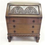 An oak carved bureau with slope front over three drawers