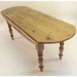 A long oval pine dropleaf kitchen table on turned supports 200cm x 79cm x 68cm (flaps down)