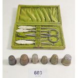 An Edwardian sewing kit with mother of pearl handles, boxed and an early bronze thimble and four