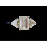 A fine platinum three stone diamond ring set central emerald cut diamond flanked by two trillion cut