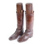 Pair of brown leather parade boots with studded soles and wooden boot stretchers