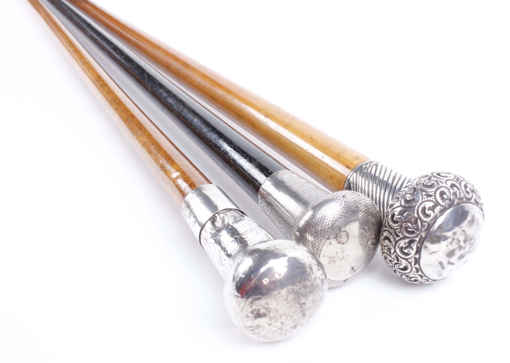 Two tapered walking canes with decorative silver pommels, together with one similar