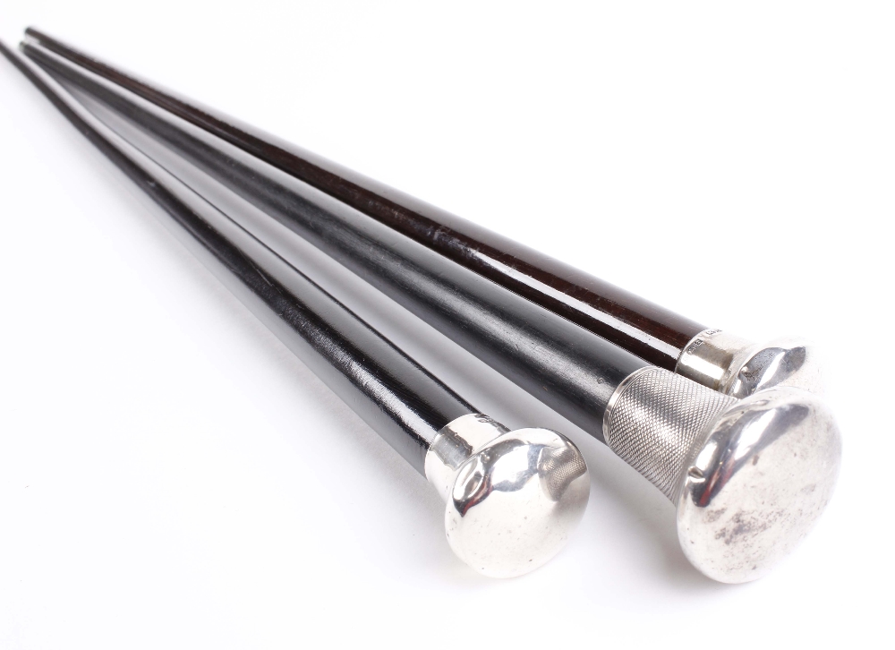 Three tapered ebonised walking canes with silver pommels and metal ferrules