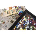 A collection of pin badges and marbles and Tazos, the vintage and modern badges in a collectors