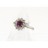 An 18ct gold ruby and diamond set cluster ring, the oval mixed cut ruby in four claw setting