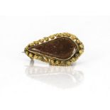 A yellow metal and simulated sun stone navette shaped brooch, with filigree work border, with