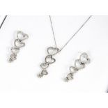 A contemporary white gold and diamond set suite of jewels, comprising a heart shaped pendant and