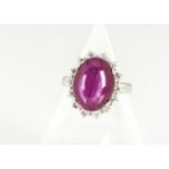 An 18ct gold ruby and diamond set cluster ring, the cabochon star ruby in four claw setting on a