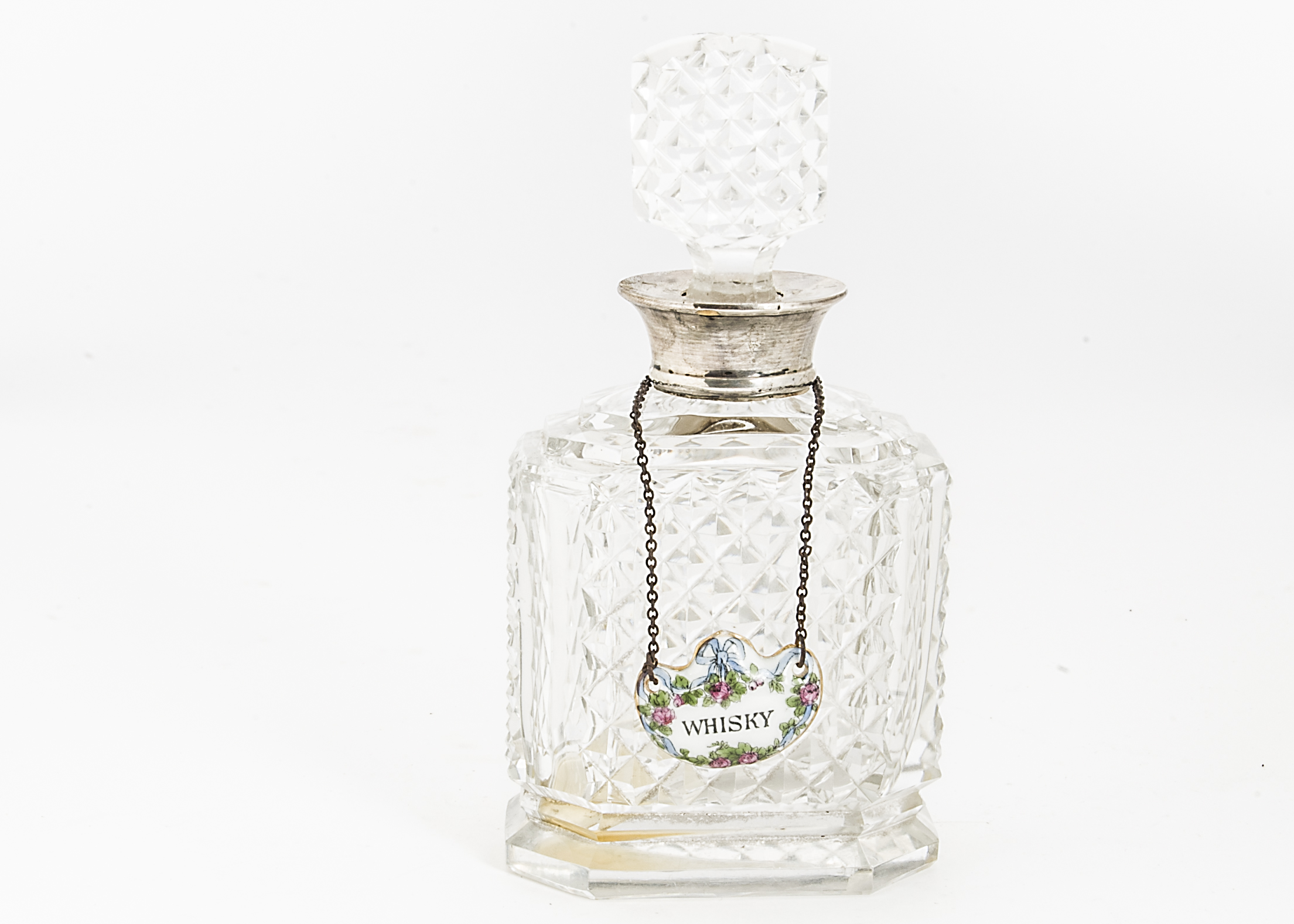 A small early 20th Century cut glass and silver collared decanter and stopper, with an enamel Whisky