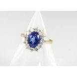 A contemporary tanzanite and diamond cluster ring, the oval mixed cut surrounded by brilliant cut