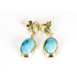 A pair of yellow metal and turquoise drop earrings, the oval polished cabochons in a plain collet