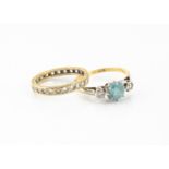 An 18ct gold three stone zircon and diamond dress ring, the central blue claw set zircon flanked