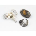 A Chinese and tiger's eye filigree brooch, marked silver verso, a silver and onyx Art Nouveau brooch