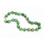 A green jade bead necklace, the knotted, strung spheres with gold clasp, each bead approximately