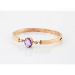 A Russian gold, amethyst and paste set bangle, the oval cut amethyst in claw setting flanked by