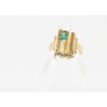 An 18ct gold and emerald set dress ring, in the retro style, the setting of linear textured design