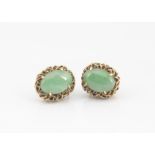 A pair of cabochon jade and 18k marked ear studs, the claw set jade centres in a basket oval mount