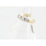 An 18ct gold three stone diamond ring, the brilliant cuts in baton settings, total diamond weight