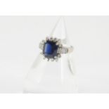 A sapphire and diamond dress ring, the step cut in four claw setting surrounded by brilliant cut and