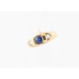 An 18ct gold sapphire and diamond three stone ring, the oval mixed cut sapphire in sunken claw