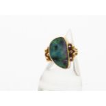 A continental black opal and yellow metal dress ring, the large oval shaped polished opal within a