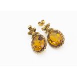 A pair of citrine drop earrings, the oval mixed cut in a rope twist setting supported on bow set