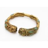 A gilded bronze coral and turquoise Chinese torque bangle, of mythical beast style with coral