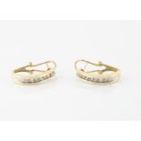 A pair of 14ct gold and diamond set earrings, the channel set brilliant cuts in a hoop setting