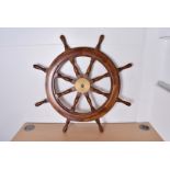 Two reproduction teak and brass ships wheels, the central brass fixing with eight turned handles,