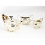 An associated Edwardian silver three piece tea set, fluted lowers, teapot by RP and sugar basin