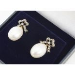 A pair of pearl and diamond earrings, the barrel shaped cultured pearls supported on diamond bows,