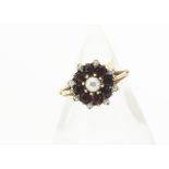 A contemporary garnet and pearl yellow metal cluster ring, the central claw set pearl surrounded