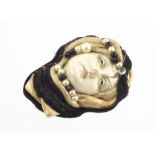 A Venetian late 20th Century mixed media brooch, modelled as a young female face, within a leather