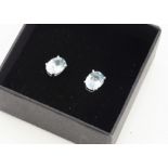 A pair of oval topaz ear studs, the light blue oval mixed cuts in four claw setting, boxed