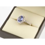 A 9ct gold tanzanite and diamond cluster ring, the oval mixed cut claw set blue tanzanite surrounded