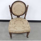 A late Victorian walnut framed nursing chair, circular back supported by two turned columns, blush