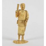 A Meiji period Japanese okimono of a Samurai , holding an implement and sword, the base with