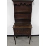 An antique oak dresser, of small proportions, top with enclosed panel back, two shelves with moulded