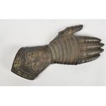 A metalwork hand taking the form of a Knight's gauntlet, with chivalric decoration of griffins above