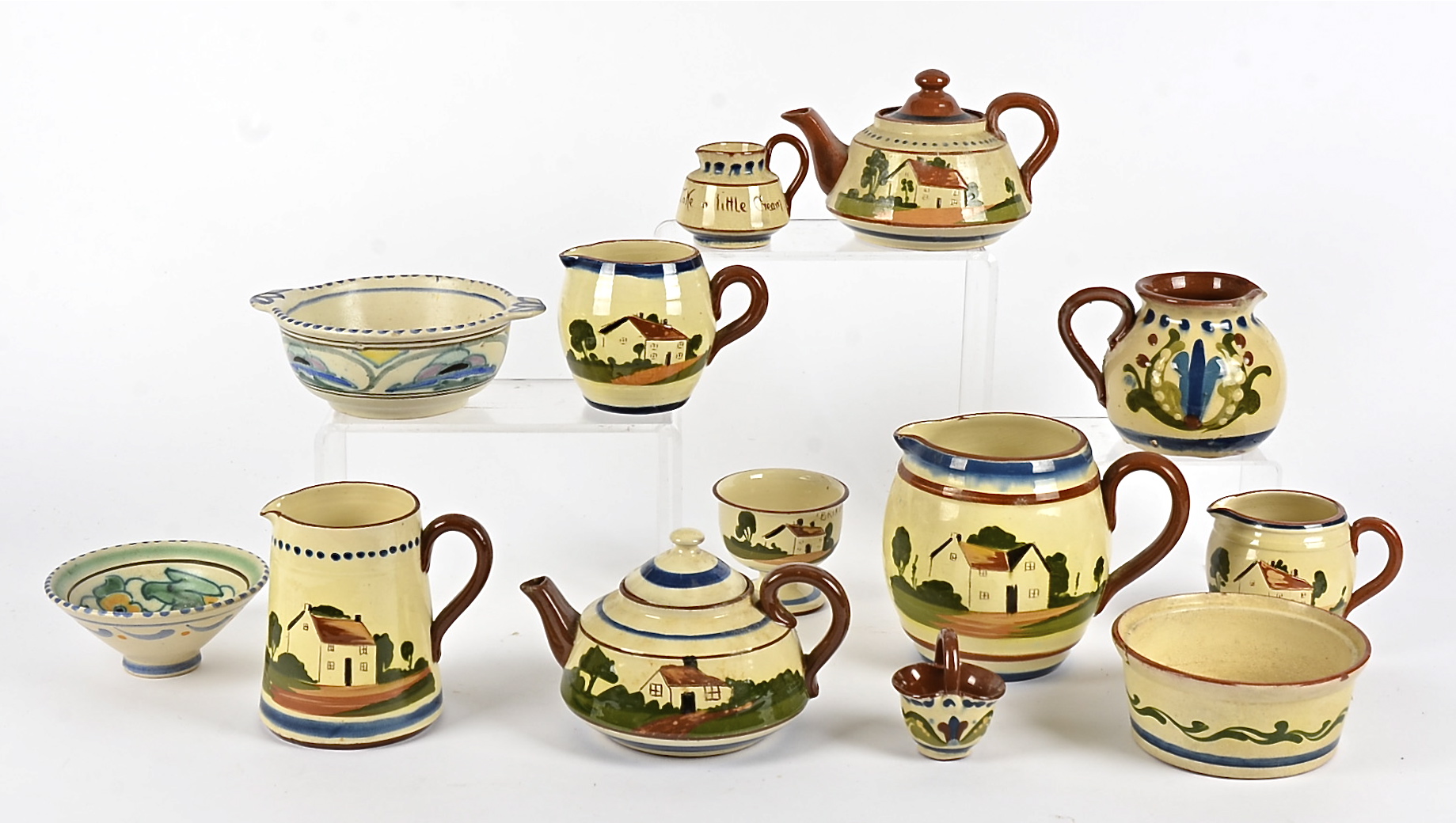 A quantity of Devonware terracotta motto decorated, including teapots, leamonade jugs, milk jugs and