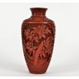 A cinnabar lacquer vase, with a depiction of plantlife rising above rocks, height 21cm