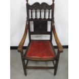 A late 19th Century oak and elm elbow chair, with carved back panel and rail, red studded upholstery