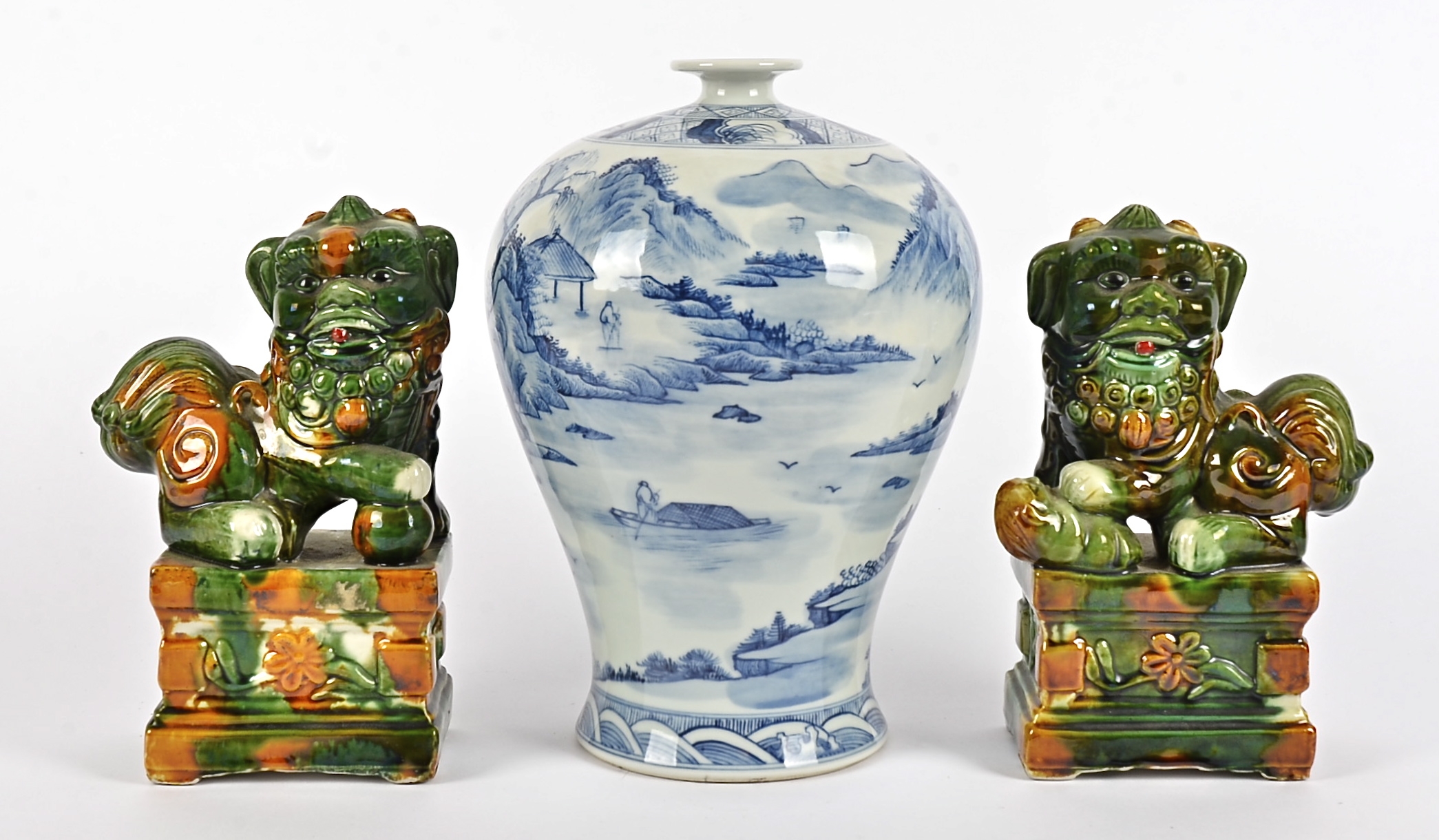 A pair of Chinese sancai glazed Dogs of Fo raised on plinths, each holding an object underfoot,