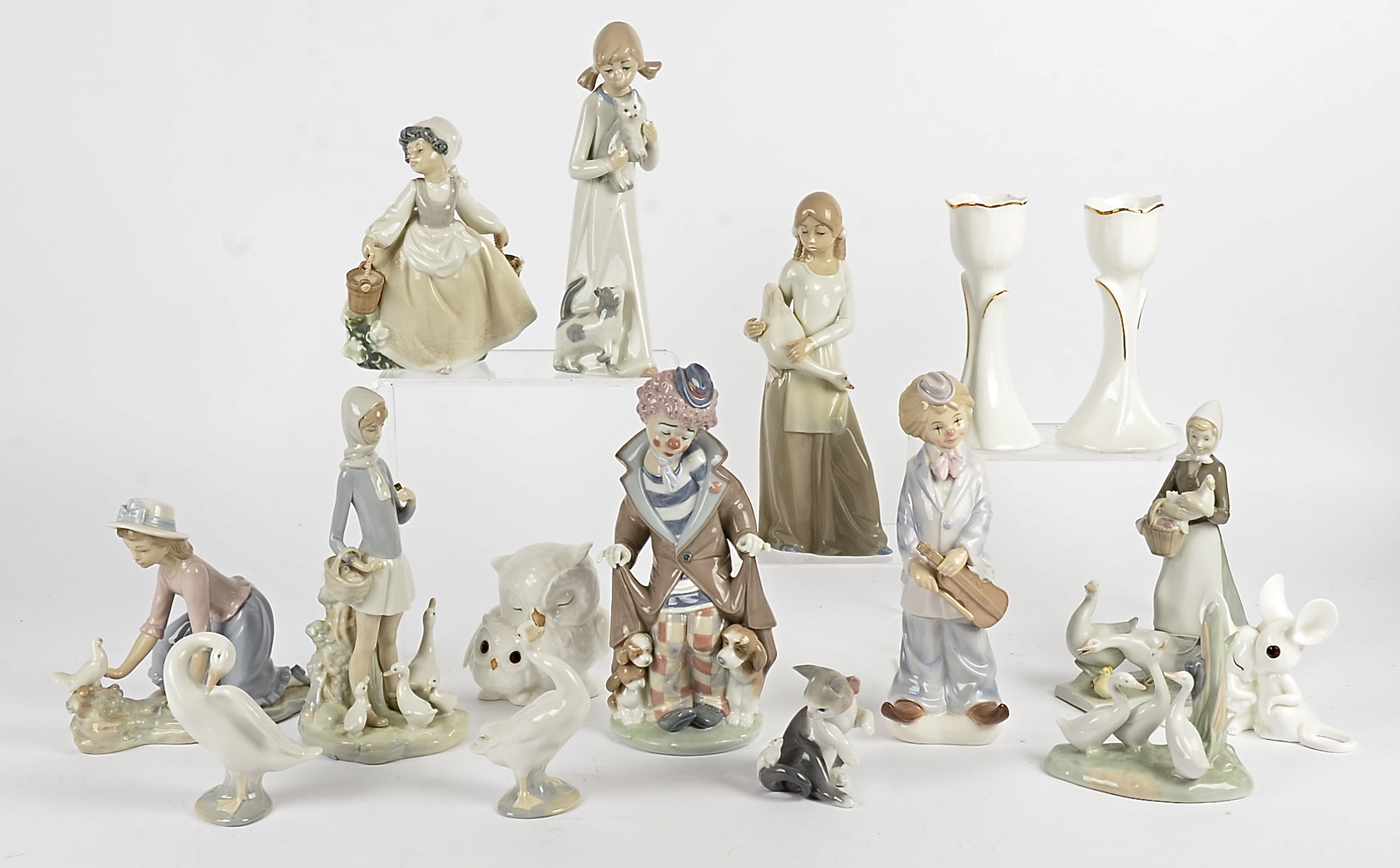 A small group of Lladro ceramics, including girls and geese, kittens and clowns and a few other