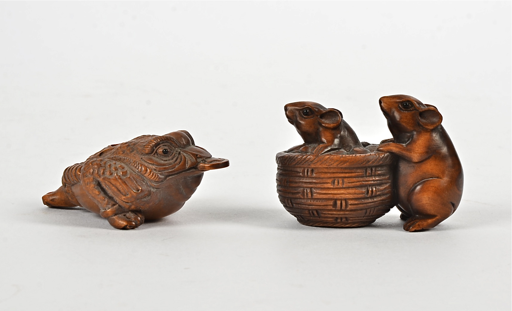 Two Japanese boxwood netsuke, one in the form of a toad holding a coin in its mouth, length approx