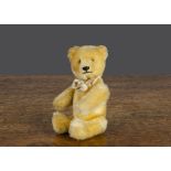 A small Schuco 1950s yes/no teddy bear, with golden mohair, brown and black glass eyes, black