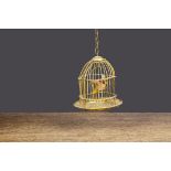 A dolls’ house gilt-metal bird cage, with wax parrot —3in. (7.5cm.) high