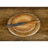 A carved pine ‘Waste Not Want Not’ bread board, —11¾in. (30cm.) diameter; and a Mappin Brothers